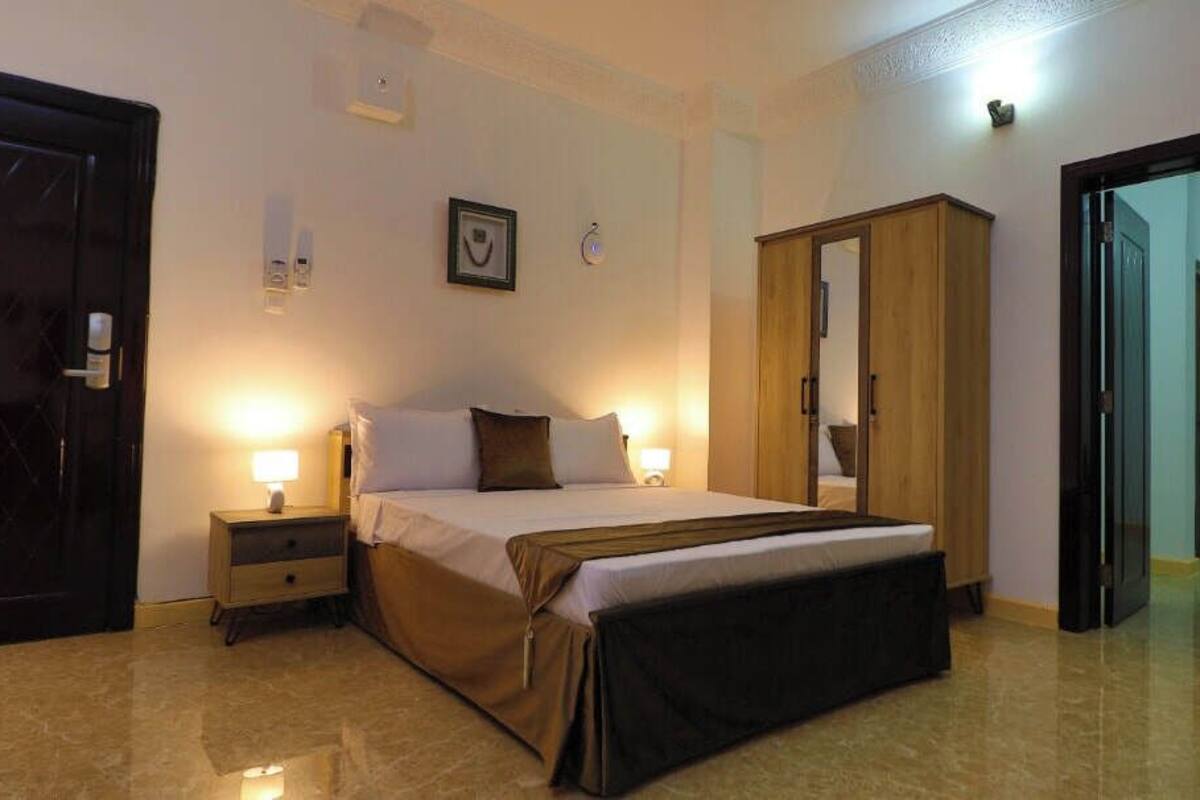 A bedroom with a bed, bedside tables, a wardrobe, and a door.