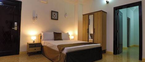 Un dormitorio con cama, mesitas de noche, armario y puerta.