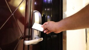 A hand inserting a key into a door lock.
