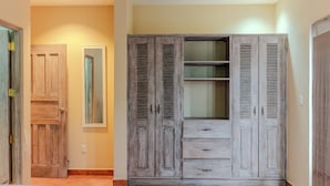 A bedroom with a bed, wooden wardrobe, and a mirror. - king Standart pool view (Tola)