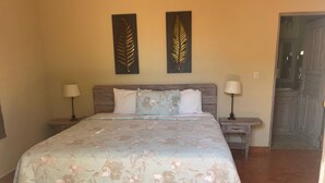A bedroom with a large bed, two nightstands, two wall-mounted lamps, and two decorative leaf wall art pieces. - king Standart pool view (Tola)