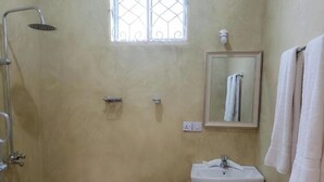 Ein Badezimmer mit Dusche, Waschbecken, Spiegel und Fenster.