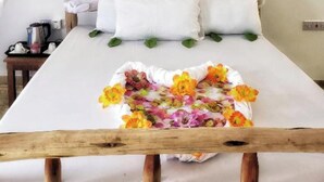 A bed with a white canopy and pillows, a wooden headboard, and a floral arrangement on the bed. - Serenity Boutique Hotel (Paje)