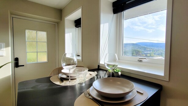 Ein Essbereich mit Tisch für zwei Personen, einem Fenster mit Blick auf die Landschaft und einer Tür mit Milchglasfenster.