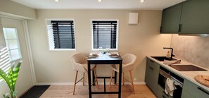 Compact kitchen with oven, sink, and windows with blinds.