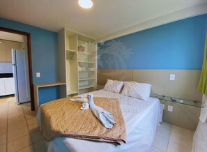A hotel room with a bed, a wardrobe, a small table, and a wall with a palm tree mural. - Marupiara Suites (Ipojuca)