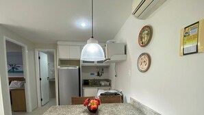 Ett kök med ett kylskåp, en hängande lampa och en väggmonterad luftkonditioneringsanläggning.