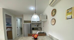 A kitchen with a refrigerator, a hanging light fixture, and a wall-mounted air conditioner. - Marupiara Suites (Ipojuca)