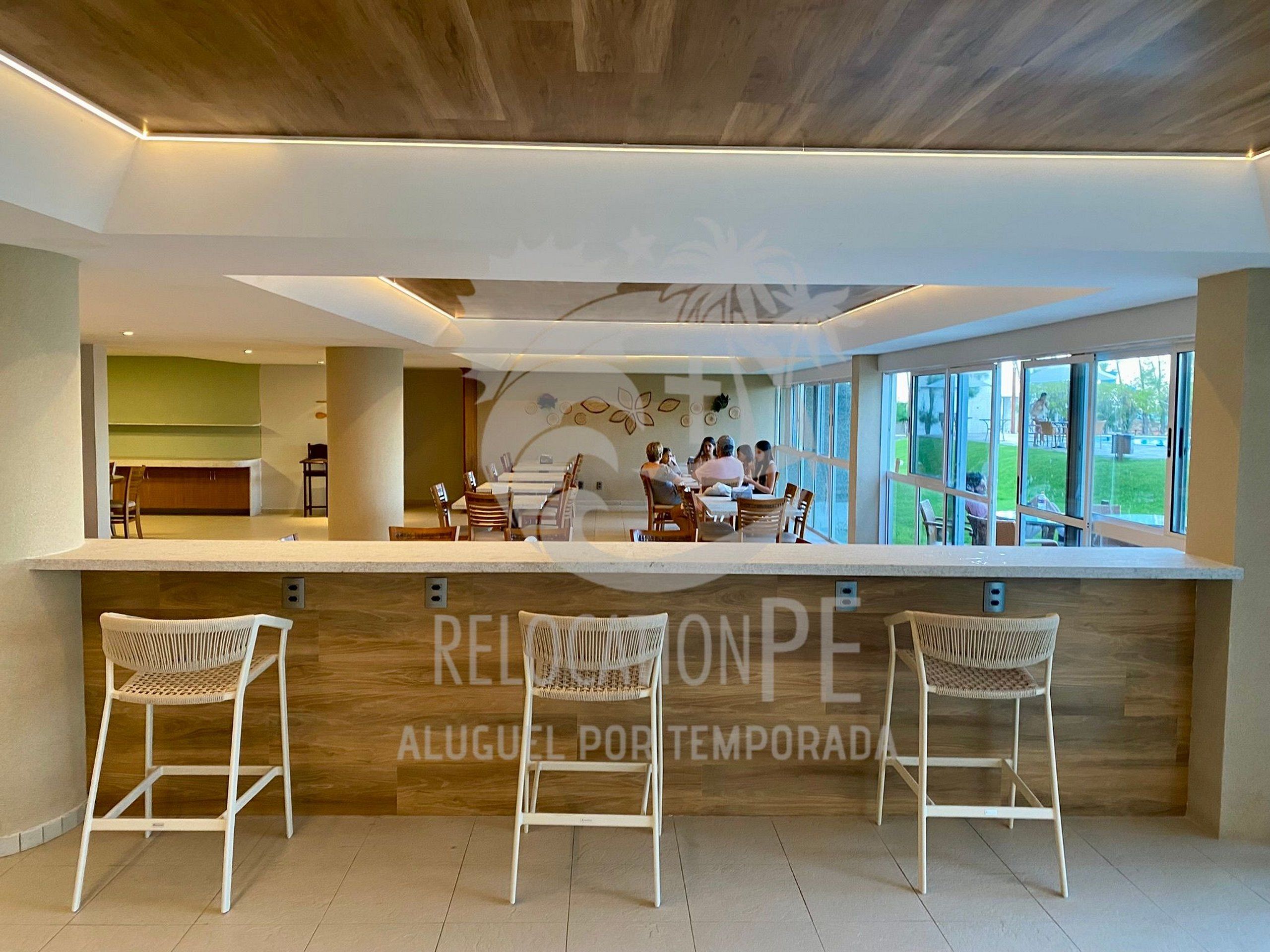 A modern reception area with a wooden reception desk, white wicker bar stools, and a view of the outdoors.