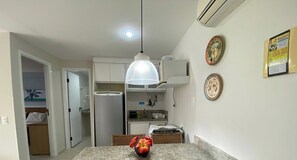 A kitchen with a refrigerator, microwave, and a hanging light fixture. - Marupiara Suites (Ipojuca)
