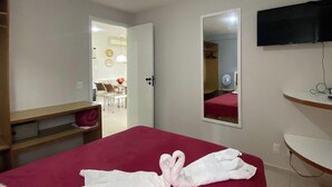 Ett hotellrum med en säng, en spegel, en tv och ett skrivbord.