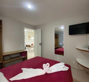 A hotel room with a bed, a mirror, a TV, and a desk. - Marupiara Suites (Ipojuca)