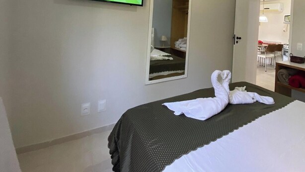Una habitación de hotel con cama, televisión montada en la pared y un espejo.