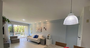 A modern living room with a sofa, a dining table, and a pendant light.