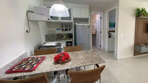Una cocina compacta con una mesa, sillas y una lámpara colgante.