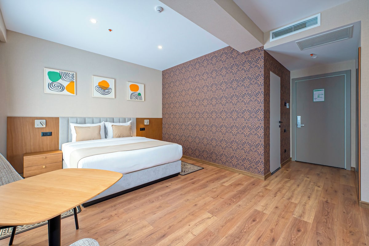 Une chambre d’hôtel moderne avec un grand lit, un plancher en bois et des œuvres d’art accrochées au mur.