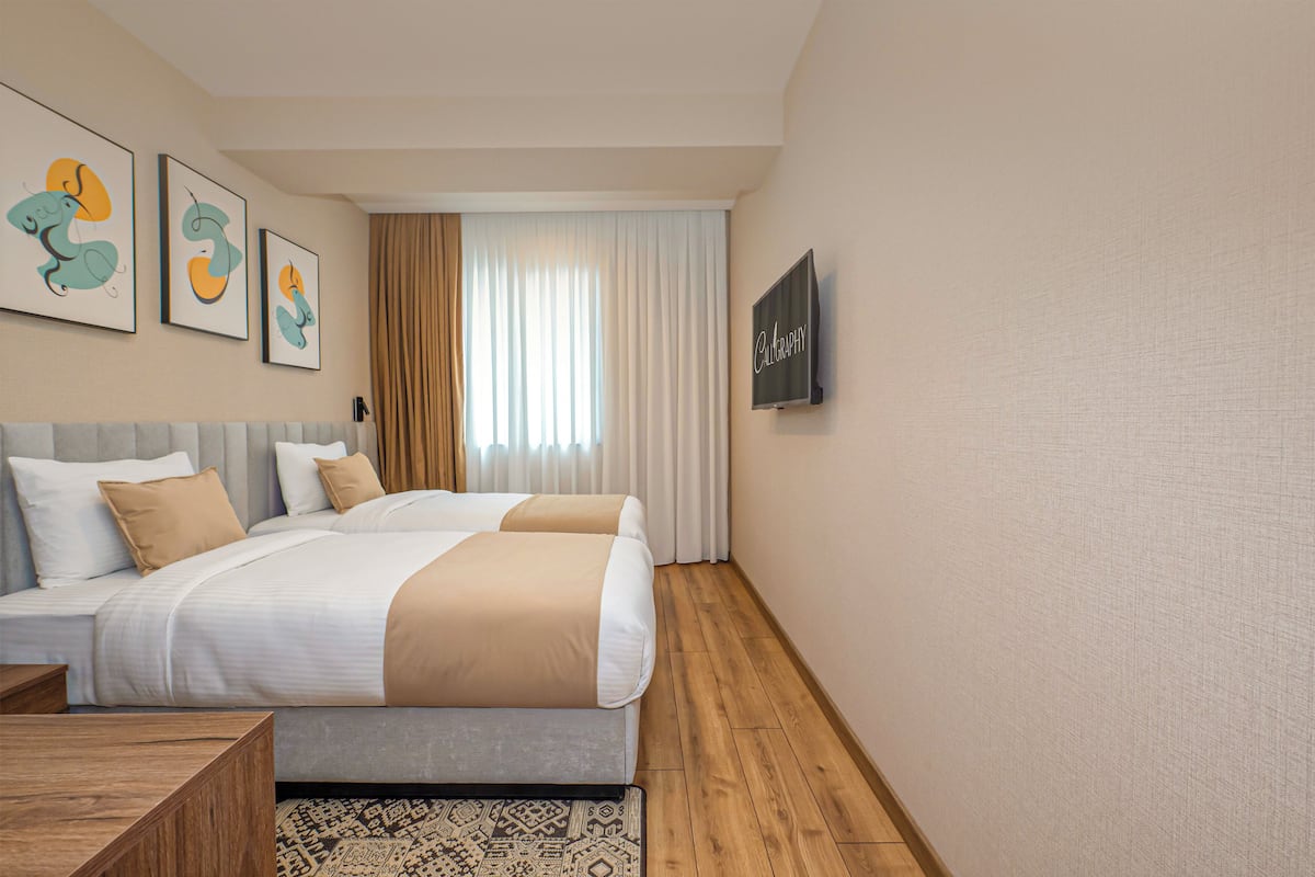 Une chambre d’hôtel moderne avec un grand lit, une télévision et des œuvres d’art accrochées au mur.