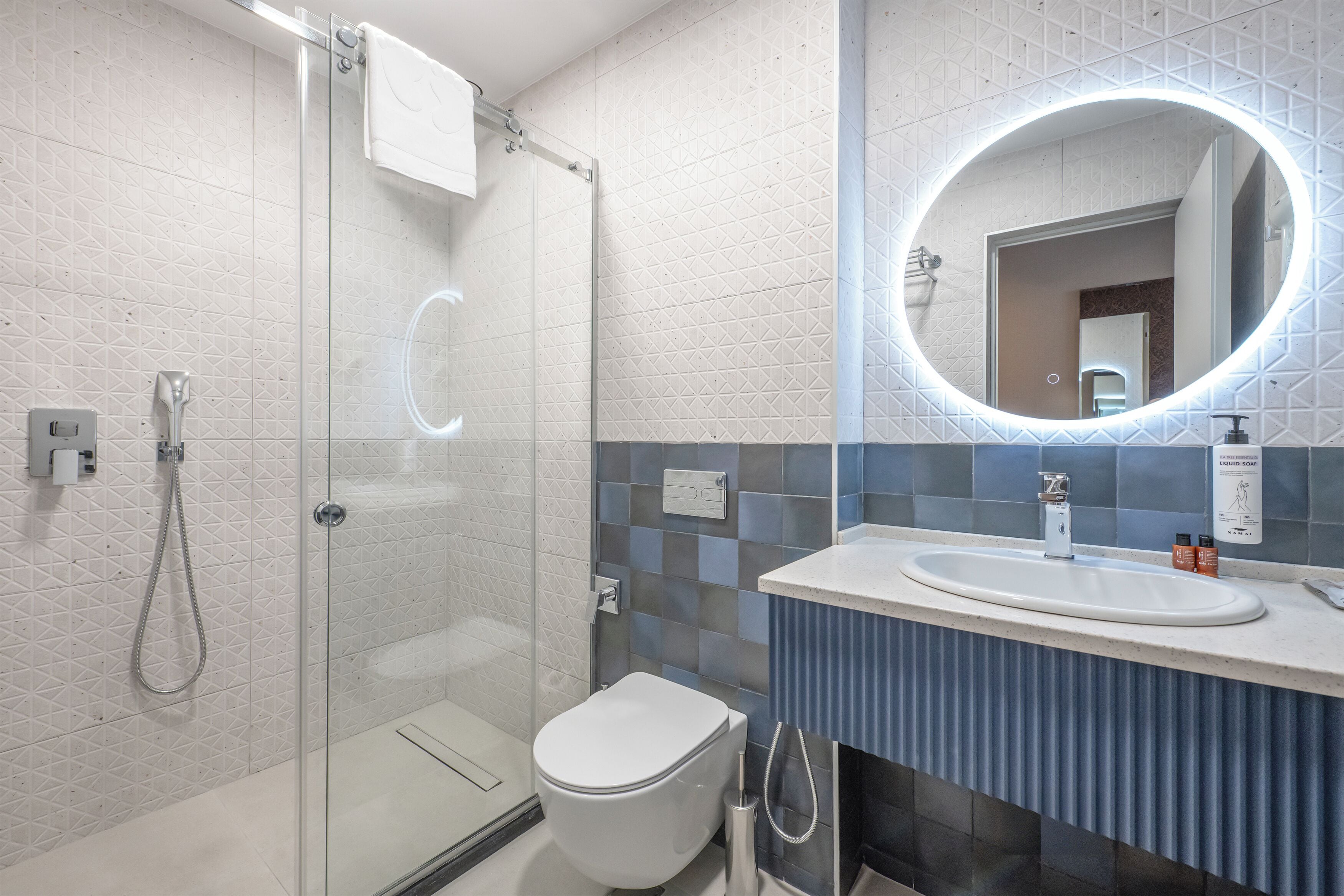 A modern bathroom with a glass shower enclosure, a white toilet, and a vanity with a mirror.