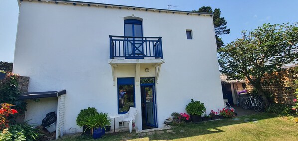 A white building with a blue balcony and a door.