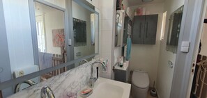 A bathroom with a marble sink, a large mirror, a toilet, and a cabinet.