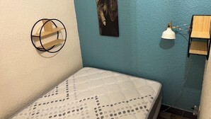 A bedroom with a bed, a wall-mounted shelf, a wall clock, and a picture. - Charming apartment close to everything (Cavalaire-sur-Mer)