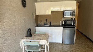 A compact kitchen with white cabinets, a microwave, a coffee maker, and a sink. - Charming apartment close to everything (Cavalaire-sur-Mer)