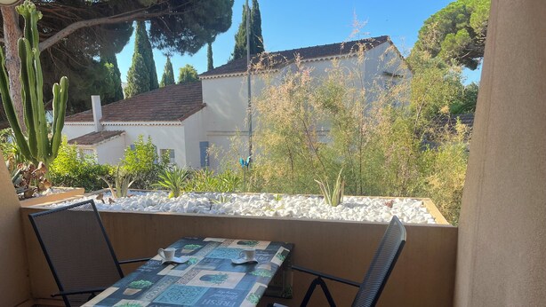 An outdoor patio with a table and chairs, surrounded by plants and a white stone wall. - Charming apartment close to everything (Cavalaire-sur-Mer)