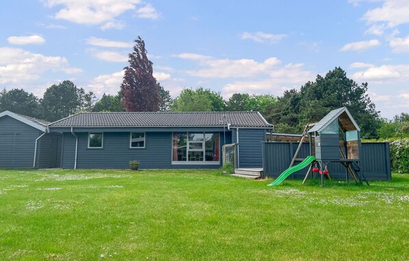 A residential house with a tiled roof, a front porch, and a small play area with a slide.