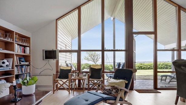 A spacious living room with a large window, a bookshelf, and a comfortable seating area. - Beautiful home in Egernsund with sauna (Egernsund)