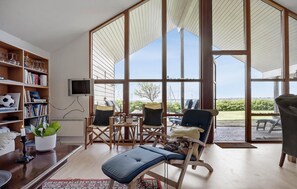 A spacious living room with a large window, a bookshelf, and a comfortable seating area. - Beautiful home in Egernsund with sauna (Egernsund)