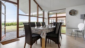 A dining area with a table set for four, large windows, and a view of the outdoors. - Beautiful home in Egernsund with sauna (Egernsund)