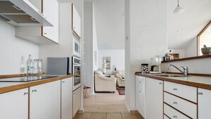 A narrow kitchen with white cabinets, a built-in oven, and a coffee maker. - Beautiful home in Egernsund with sauna (Egernsund)