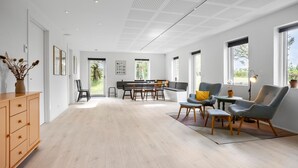En rummelig stue med trægulv, spiseplads med stole og bord, sofa og skab.