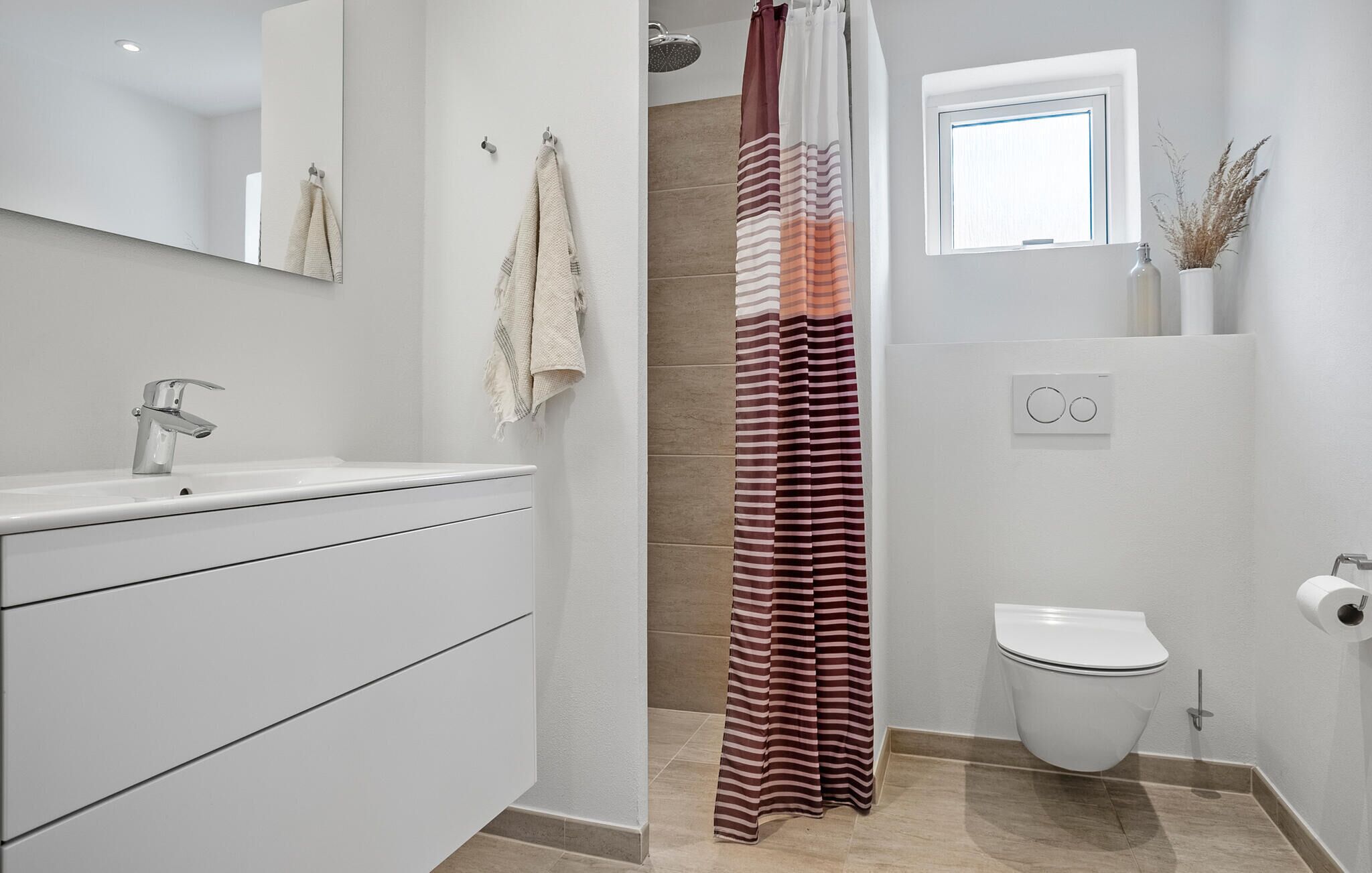 A modern bathroom with a shower curtain, a toilet, and a sink with a mirror.