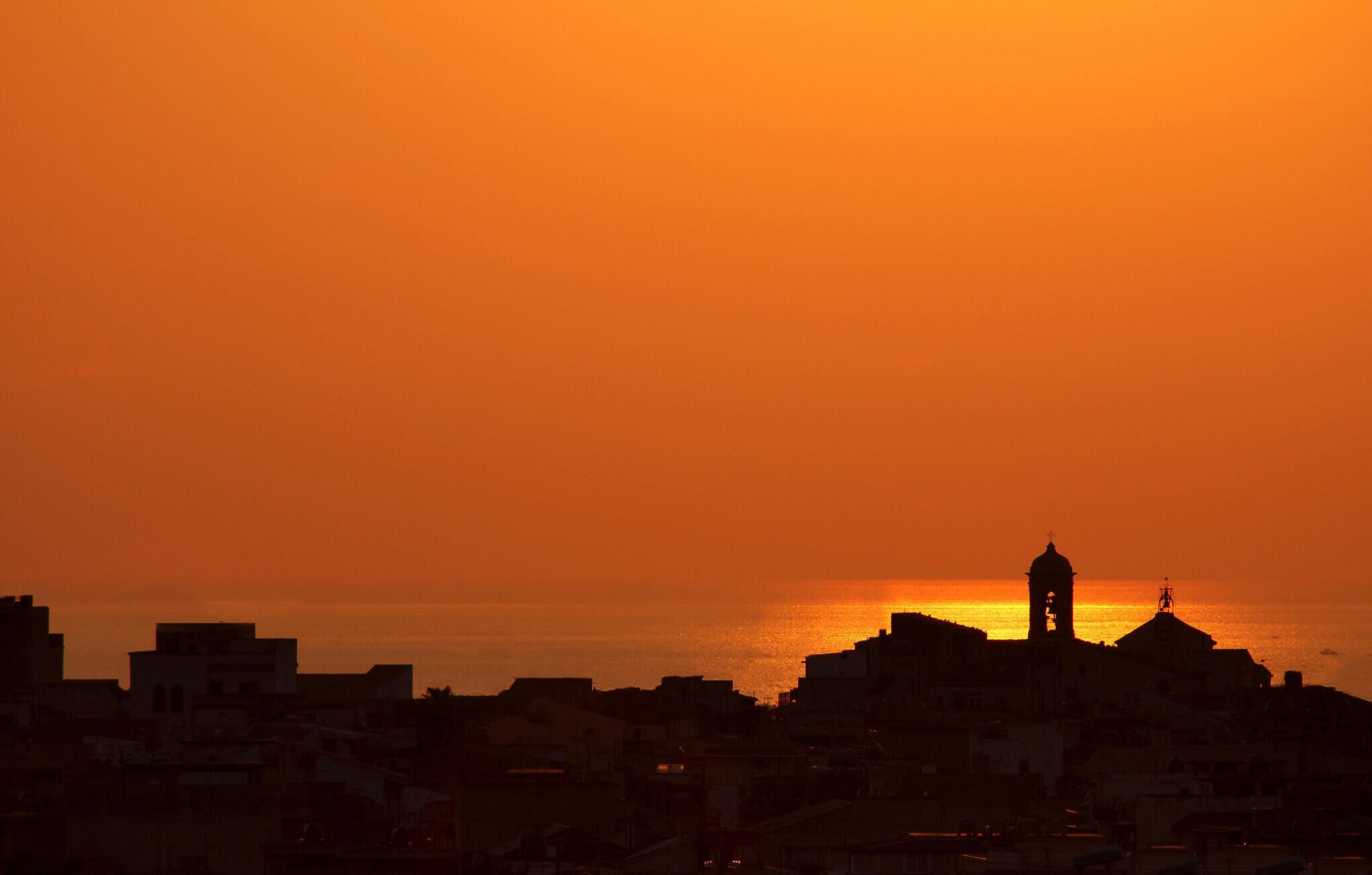 A cityscape silhouette at sunset with a prominent tower.
