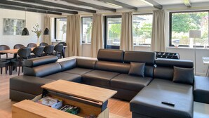 En moderne stue med en hjørnesofa, et træsofabord og et spiseområde med stole og et bord.