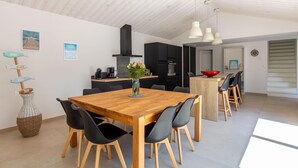 Una cocina moderna con armarios negros, una mesa de comedor de madera y sillas negras. Hay un jarrón con flores sobre la mesa.