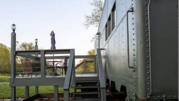 Un vagó de tren quiet amb una escala que mena a una plataforma amb seients a l'aire lliure.