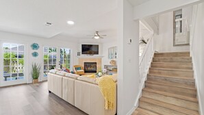 A spacious living room with a large sofa, a fireplace, and a TV mounted above it. - Spacious Pet-Friendly Beach Home (Cape Canaveral)