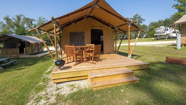Een tent met een houten terras en een tafel met stoelen.