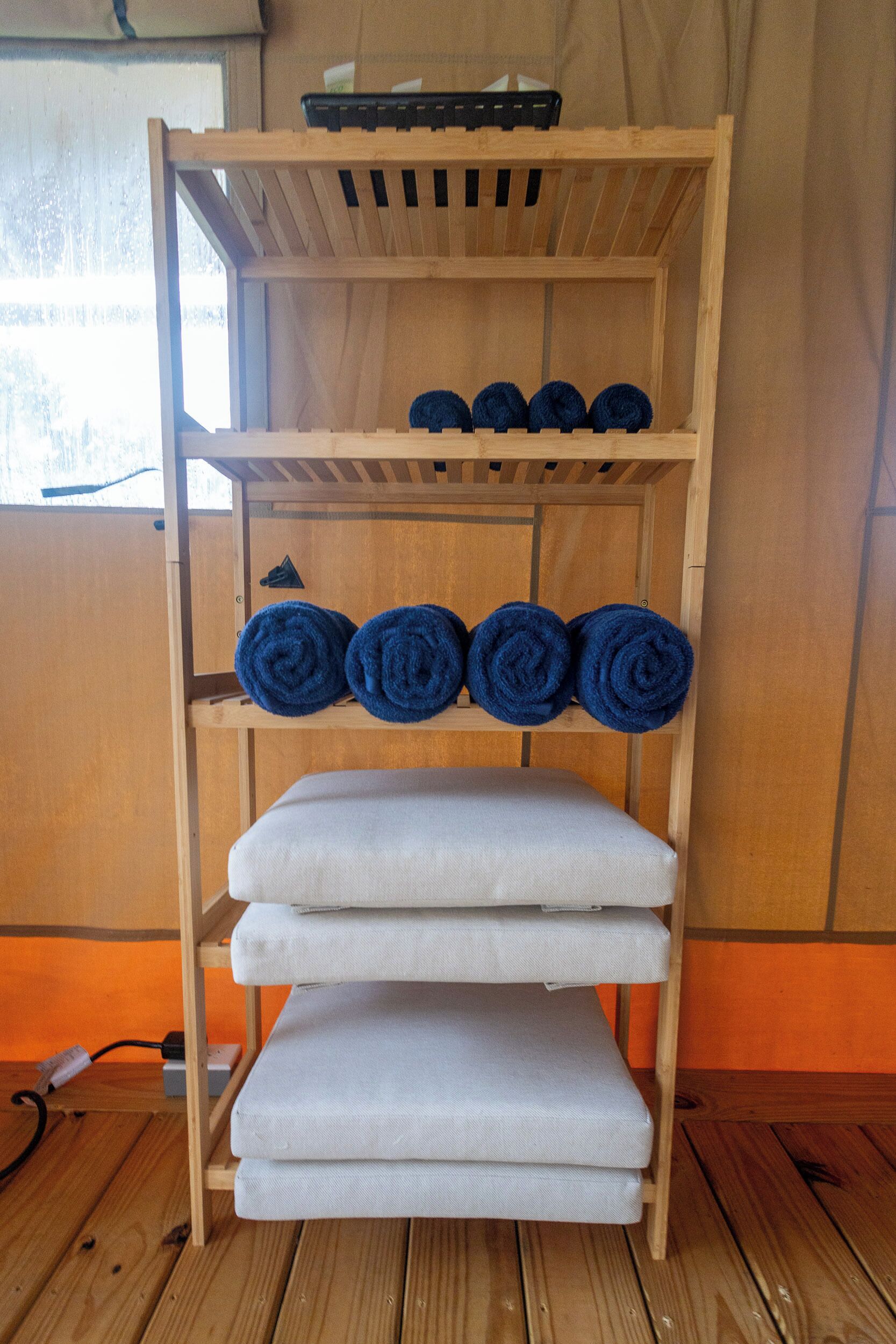 Une étagère en bois avec des serviettes roulées et du linge de maison plié.