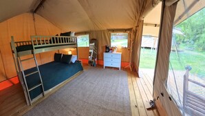 Ein gemütliches Zelt mit Etagenbett, kleinem Schreibtisch, Stuhl und Blick ins Freie.