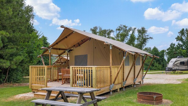 Ein Campingplatz mit einer Holzterrasse, einem Picknicktisch und einem Zelt.