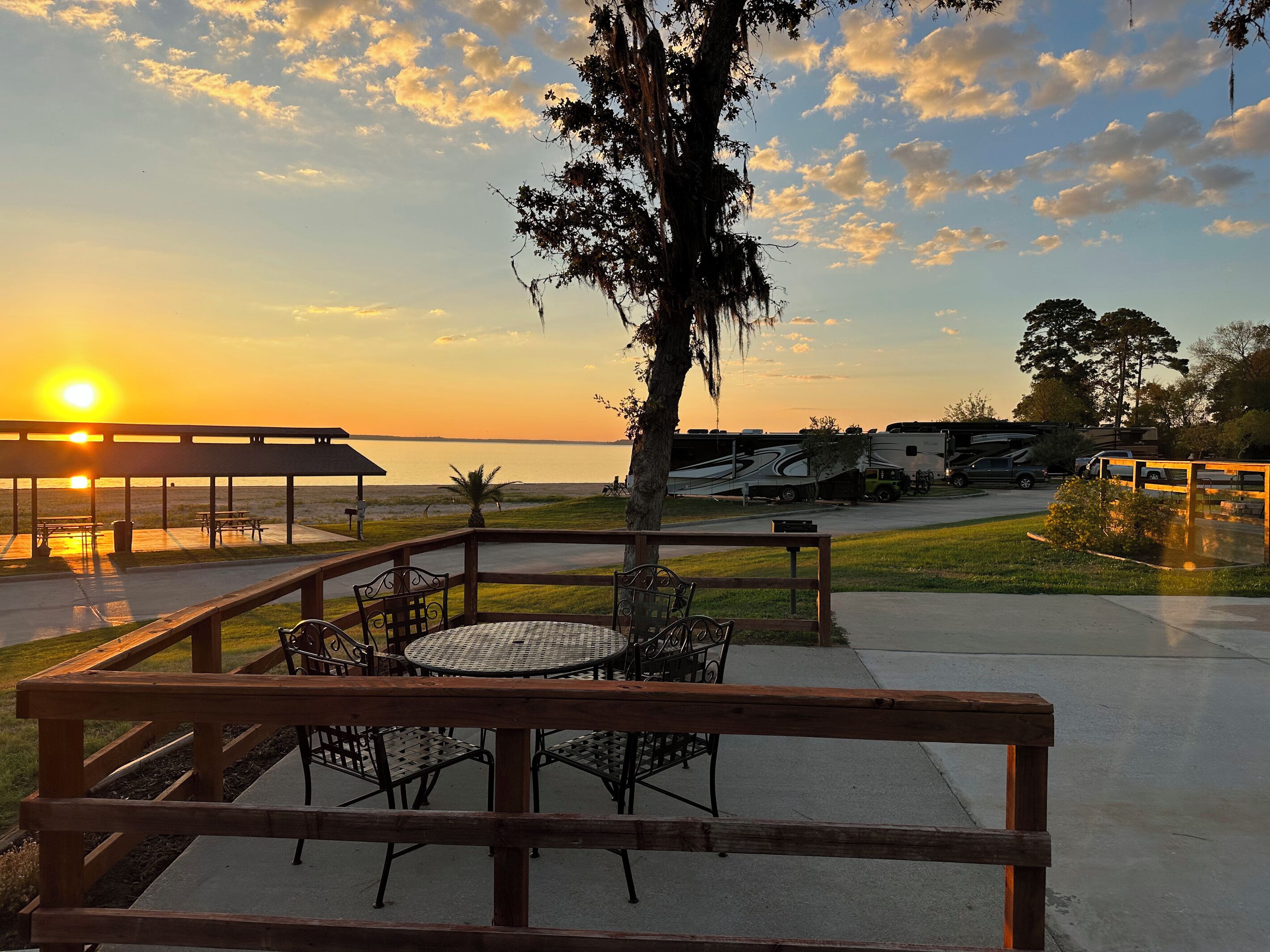 A sunset view with a picnic area, tables, chairs, and RVs parked nearby.