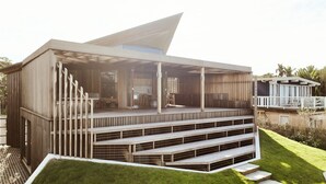 A modern house with a large deck, multiple levels, and a sloped roof.