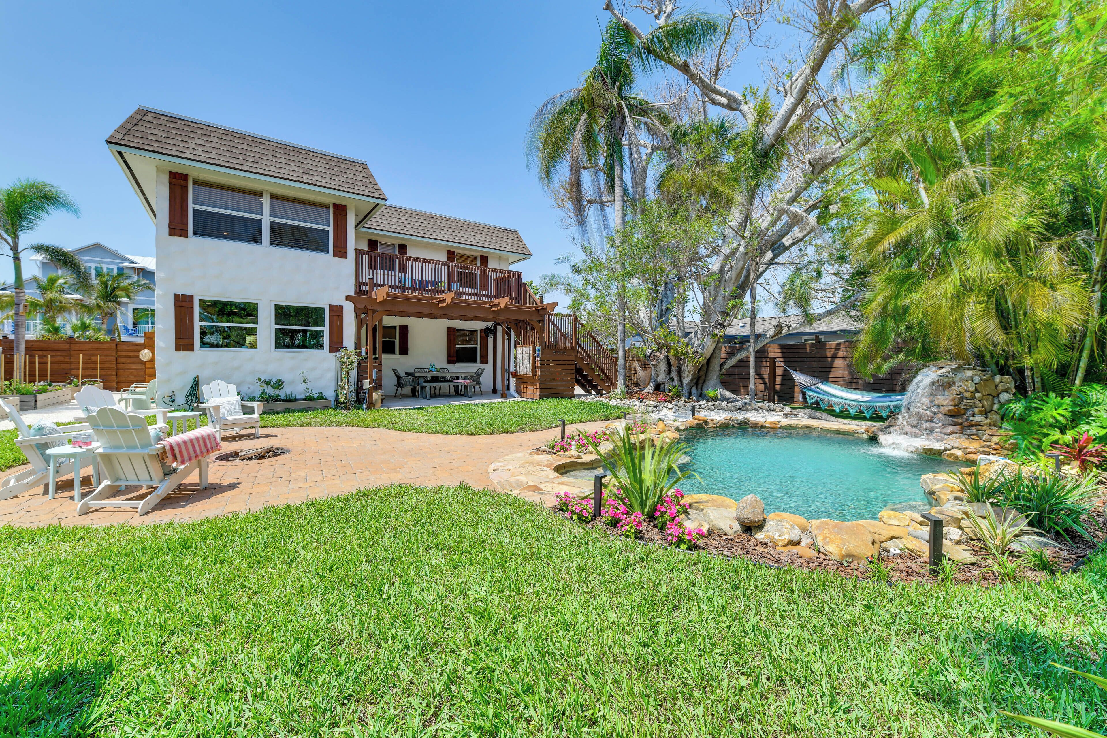 A two-story house with a balcony, a backyard with a swimming pool, and a waterfall feature.