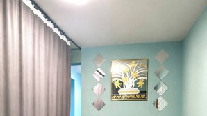 A room with a beige sofa, a blue pillow, a wall-mounted picture, and a mirror.