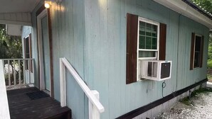 A house with a porch, wooden steps, and an air conditioning unit.