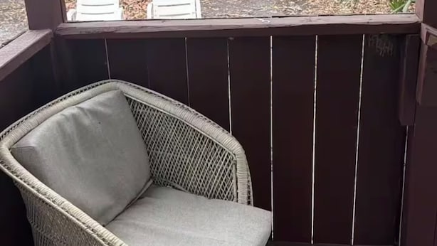 A wicker chair with a cushion on a wooden deck.
