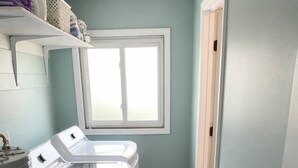 A laundry room with a washer and dryer, a window, and a door.